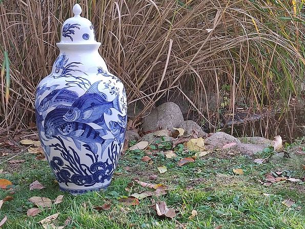 "Deckelvase Fische" aus Meissener Porzellan, weiße Vase mit blauen Fischen steht in der Natur 