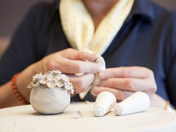 ein Bossierer formt Schneeballblüten aus Meissener Porzellanmasse